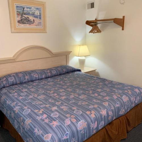 a bedroom with a bed with a blue comforter at Roman Holiday Resort in North Wildwood