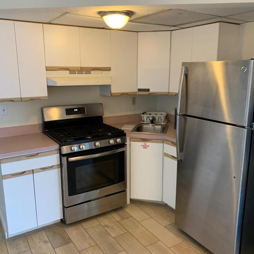 a kitchen with a stainless steel refrigerator and white cabinets at Roman Holiday Resort in North Wildwood