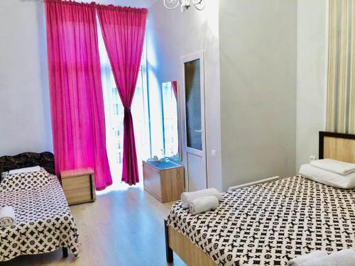 a bedroom with two beds and pink curtains at U Morya Guesthouse in Sukhum