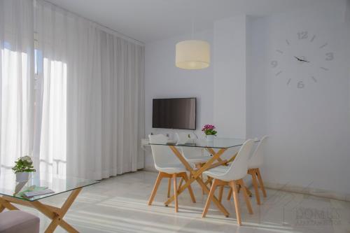 a dining room with a table and chairs and a clock at Domus Apartamentos Granada con parking gratuito en pleno centro in Granada