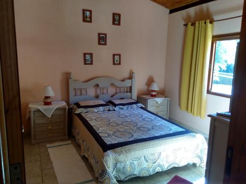 a bedroom with a bed and two tables and a window at Pousada e Pesqueiro Trem do Peixe in Monte Alegre do Sul