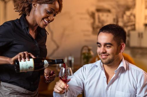 a woman pouring a man a glass of wine at Mercure Lyon Est Chaponnay in Chaponnay