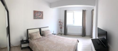 a white bedroom with a bed and a mirror at Hanul Piratilor Promenada Apartament in Mamaia Nord