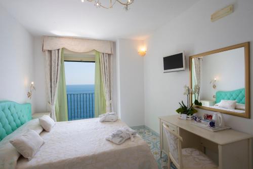 a bedroom with a bed and a desk and a mirror at Hotel Villa Maria Pia in Praiano
