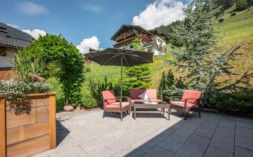 a patio with a table and chairs and an umbrella at Lebensquelle Krapfenhof in Finkenberg