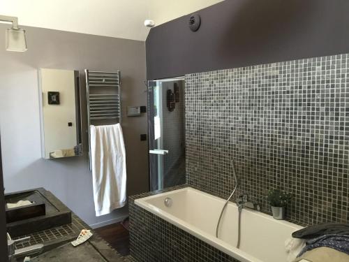 a bathroom with a tub and a tiled wall at Maison contemporaine Centre DEAUVILLE - " 3 NUITS MINIMUM" in Deauville