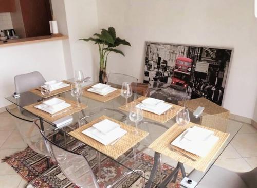 a glass table with four chairs and wine glasses at Modern 100m2 Flat 2mn Walking from Train Station in City Center, Free Parking -2A in Luxembourg
