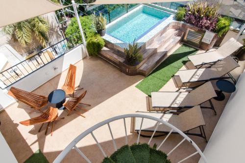 una vista aérea de una piscina con sillas y una mesa en Suites Corazon en Playa del Carmen