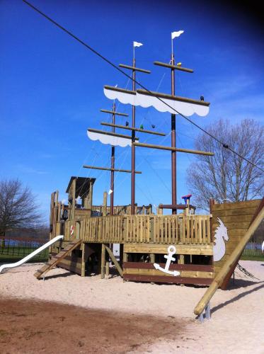 a wooden playground with a pirate ship in the sand at De Holsterhoeve in Beringen