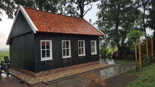 a small black house with an orange roof at Bed & Breakfast De Schoppe in Winterswijk