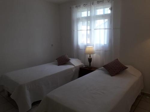 2 camas en una habitación con ventana y lámpara en Villa d'Alys, en Sainte-Rose