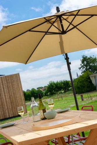 a table with wine glasses and an umbrella at De Lepelaar in Midsland
