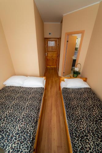 two beds in a room with wooden floors at Hotel Mare & Restaurant in Roja