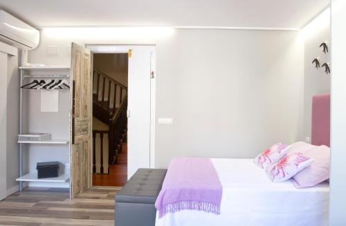 een witte slaapkamer met een bed en een trap bij Acio Tinto Loft Casco Histórico de Ourense in Ourense