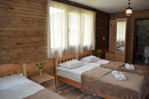 two beds in a bedroom with wooden walls and windows at Gergeti Woods in Kazbegi