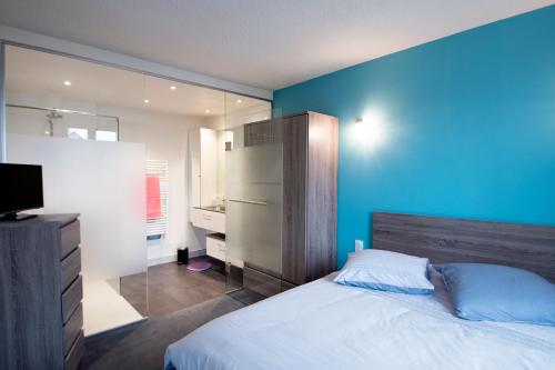 1 dormitorio con paredes azules, 1 cama y TV en Le Manoir Domaine de la Motte, en Saint-Dyé-sur-Loire