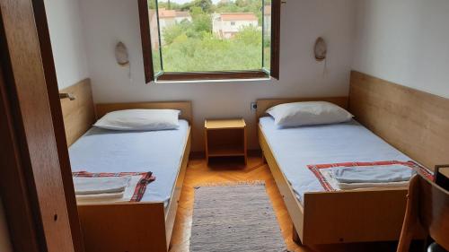 two beds in a small room with a window at Apartments Carevi Dvori in Jezera