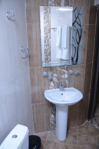 a bathroom with a sink and a mirror and a toilet at Red Hotel Yerevan Center in Yerevan