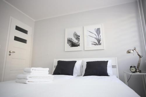 a white bedroom with a white bed with black pillows at APARTAMENT SŁOBÓDZKIEGO 7 in Świdnica