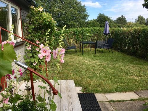 a garden with a table and an umbrella and pink flowers at Stuga Romakloster in Romakloster