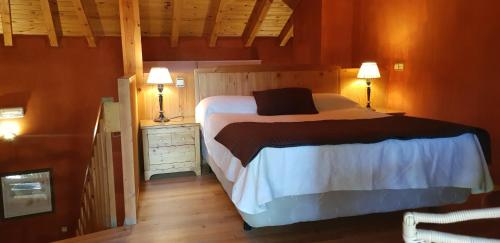 a bedroom with a bed with two lamps and a wooden floor at Hotel Sara De Ur in La Cabrera