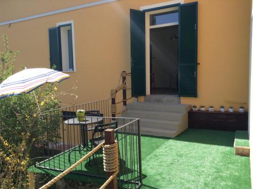 a house with a patio with a table and an umbrella at Impronte Nel Bosco in Calice al Cornoviglio