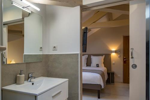 ein Bad mit einem Waschbecken und ein Bett in einem Zimmer in der Unterkunft Hotel Jean Moët in Épernay