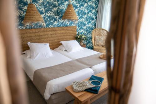 a bedroom with a bed with a blue and white wallpaper at Les Bulles de Mer - Hotel & Spa sur la Plage in Saint-Cyprien