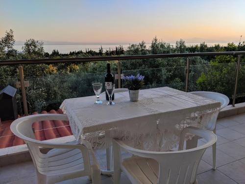 a white table with a bottle of wine and two glasses at Herodicus villa in Nea Skioni