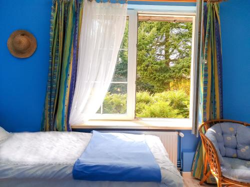 a bedroom with a window and a bed and a chair at Leśny Dworek in Darłowo
