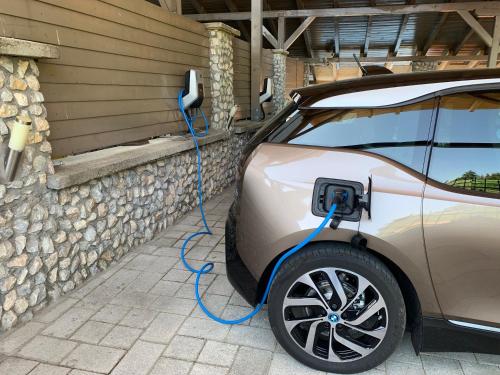 a charging electric car with a blue hose attached at Bástya Konferencia és Wellness Hotel in Miskolctapolca