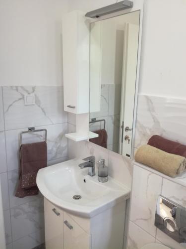 a white bathroom with a sink and a mirror at Olea in Tivat
