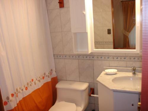 y baño con aseo blanco y lavamanos. en Turismo Vinapu en Hanga Roa
