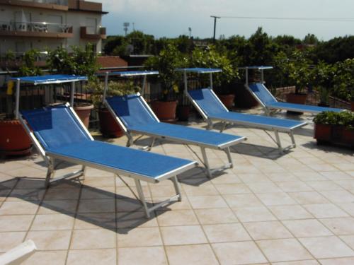 una fila de sillas azules sentadas en la azotea en Hotel Metron, en Cesenatico