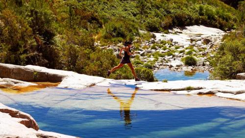 a woman running through a river in the desert at Agrinho Suites & Spa Gerês in Valdosende