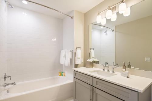 a white bathroom with a tub and a sink and a tub and a mirror at Siena at Bella Collina in Montverde