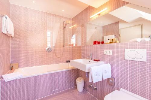 ein rosa gefliestes Bad mit einem Waschbecken und einer Badewanne in der Unterkunft Traube Blansingen in Efringen-Kirchen