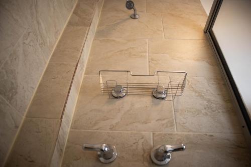 a shower with two faucets on a tile floor at California Comfort & Suites in Los Algodones