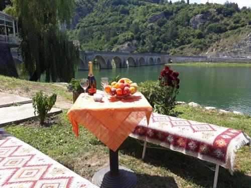 a table with a bowl of fruit and a bottle of wine at Apartment Lotika in Višegrad