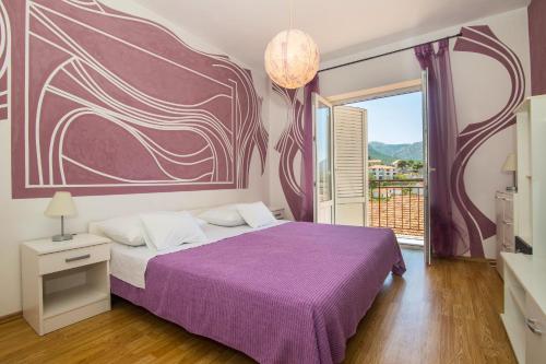 a bedroom with a purple bed with a large painting on the wall at Apartments Jelka in Jelsa