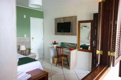 a bedroom with a bed and a desk and a mirror at Recanto do Sol in Praia de Araçatiba