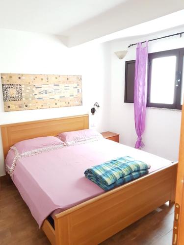 una camera da letto con un letto con una tenda viola e una finestra di LA CASA DI DAVIDE seminterrato con finestre a Àrbatax