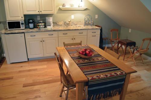 una cocina con una mesa con un tazón de manzanas. en The Lace Curtain Cottage en Chadwicks