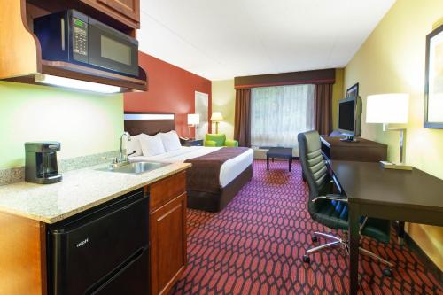 a hotel room with a bed and a desk and a sink at Baymont by Wyndham Harrisburg in Harrisburg