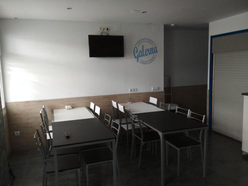 a dining room with two tables and chairs and a television at galerna aterpetxea in Zarautz