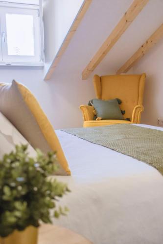a attic bedroom with a bed and a chair at Living Coimbra Corpo de Deus in Coimbra