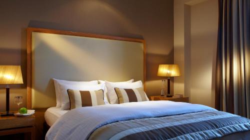 a bedroom with a large bed with two lamps at Limneon Resort & Spa in Kastoria