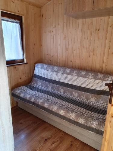 ein leeres Bett in einer Hütte mit Fenster in der Unterkunft Domki Redda in Kopań