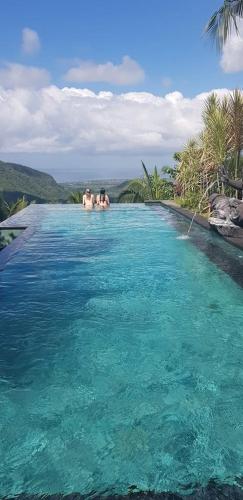 a swimming pool with people in the water at Bella Kita Mountain Retreat & Spa in Klungkung