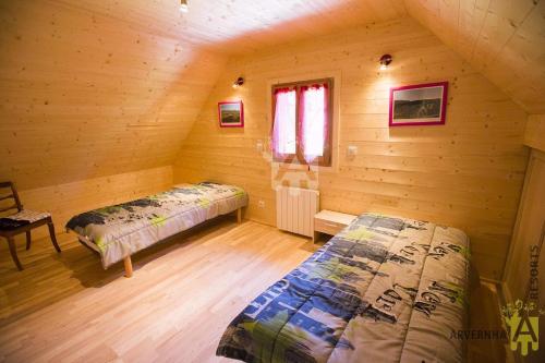 ein Schlafzimmer mit zwei Betten in einer Blockhütte in der Unterkunft Chalet des Noisettes in Murol